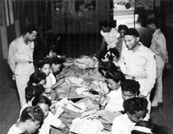 Female students at Tuskegee Institute assist the aviation cadets by sewing patches on their uniforms. 
